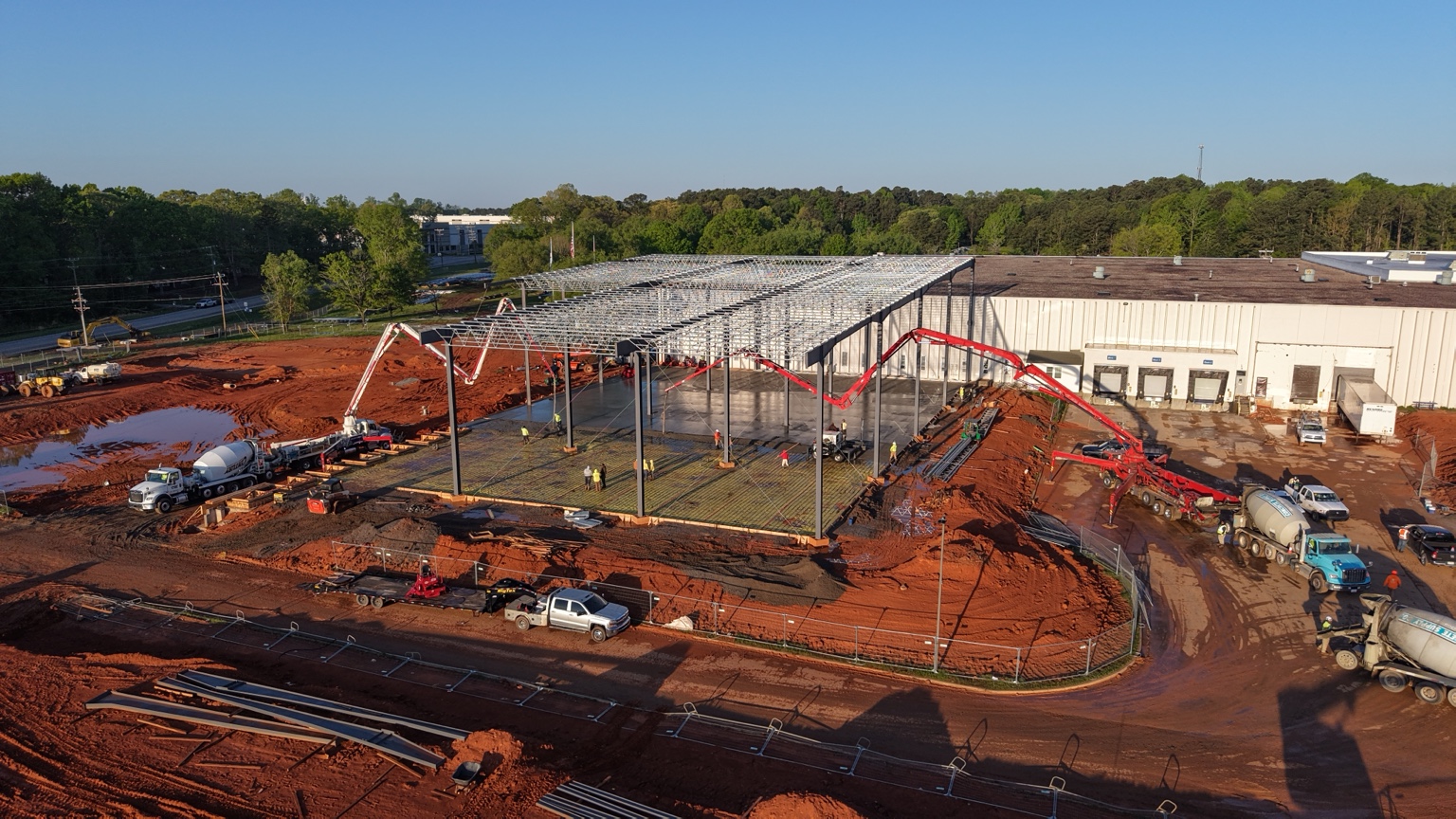 Justice Concrete crews pouring a large commercial slab under a steel building frame